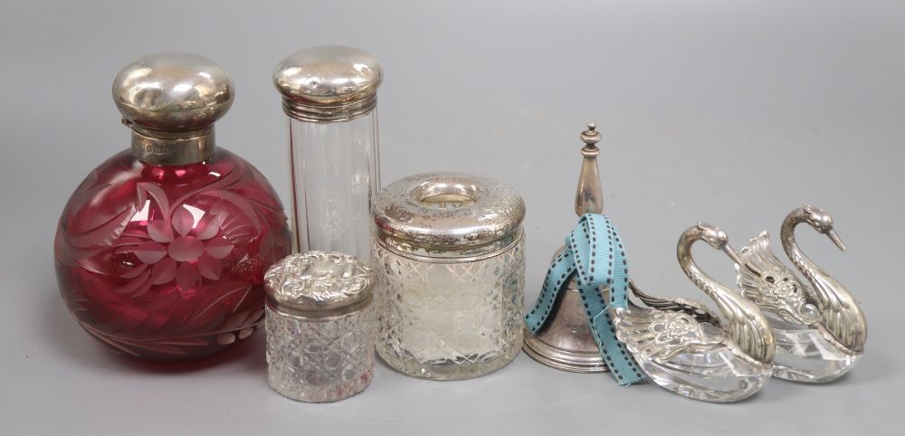 A collection of silver to include scent and toilet bottles, dressing table jars with silver tops, a pair of cut glass swan salts, a tab